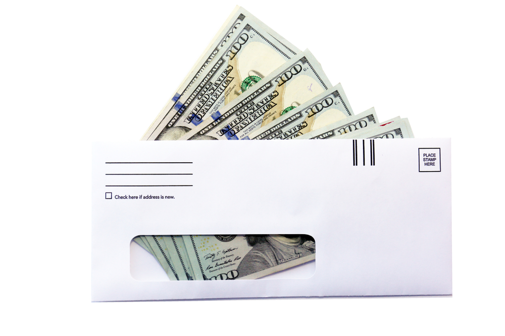 United States cash in a white mailing envelope visible through a film window.