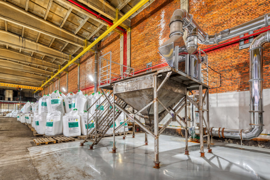 Large industrial warehouse of chemicals. Large white bags filled with powder are arranged in long rows.