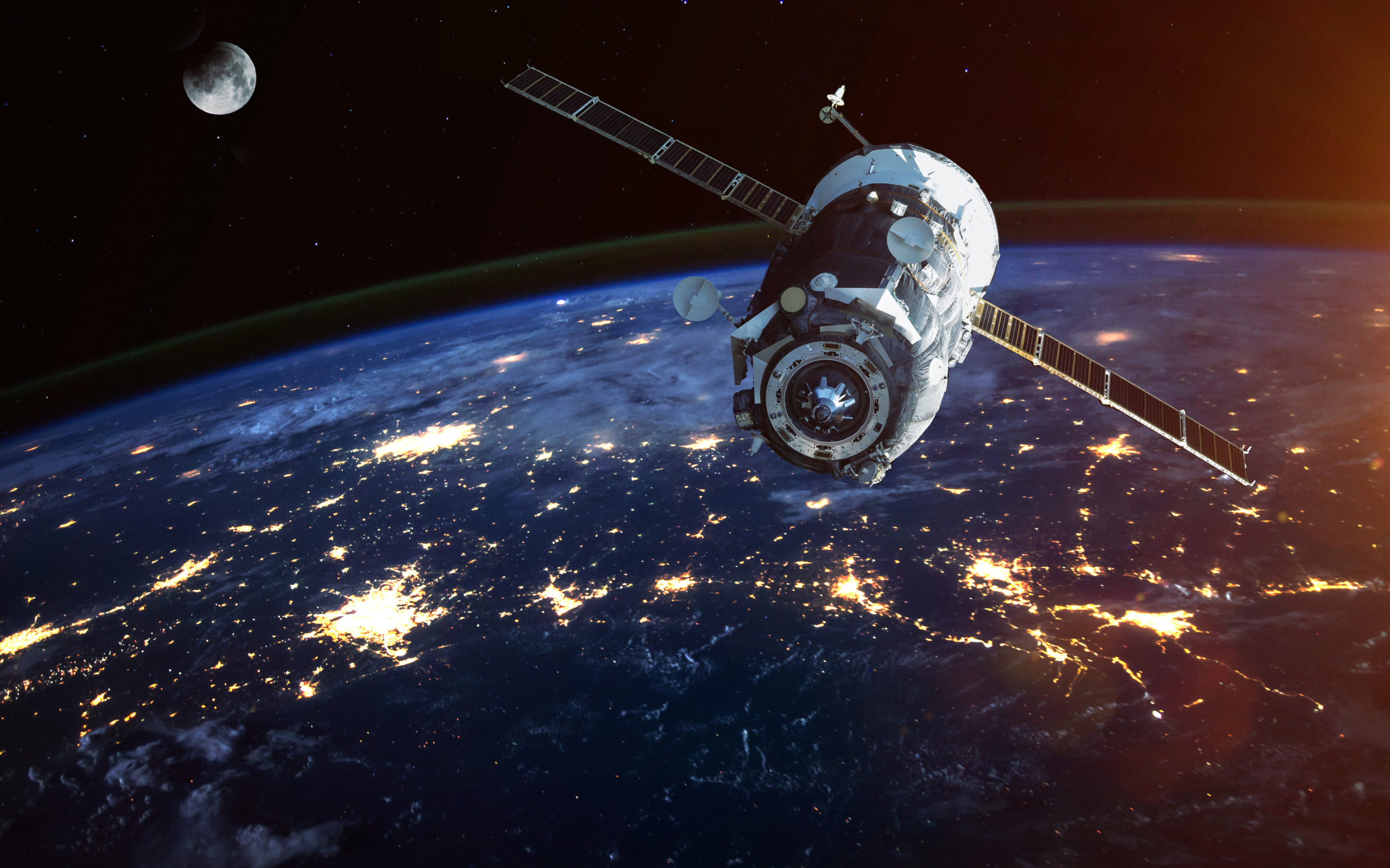 A satellite orbits Earth with lights visible from the surface